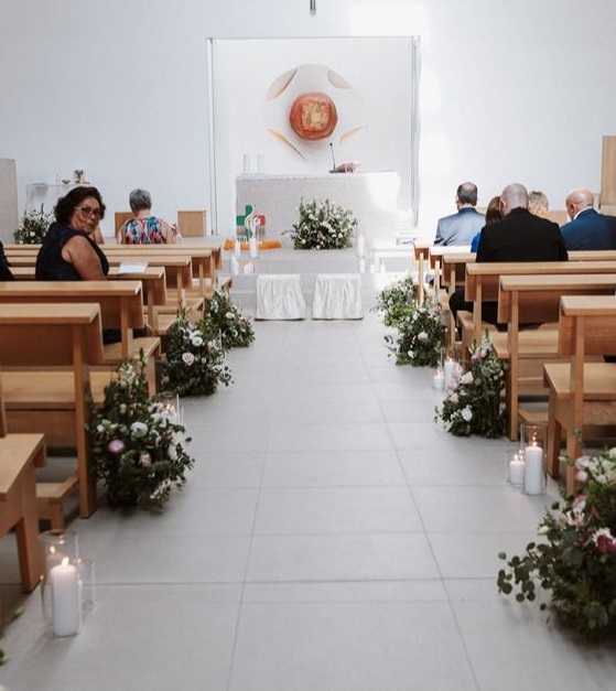 Altar de igreja decorado para casamento com arranjos de flores brancas.